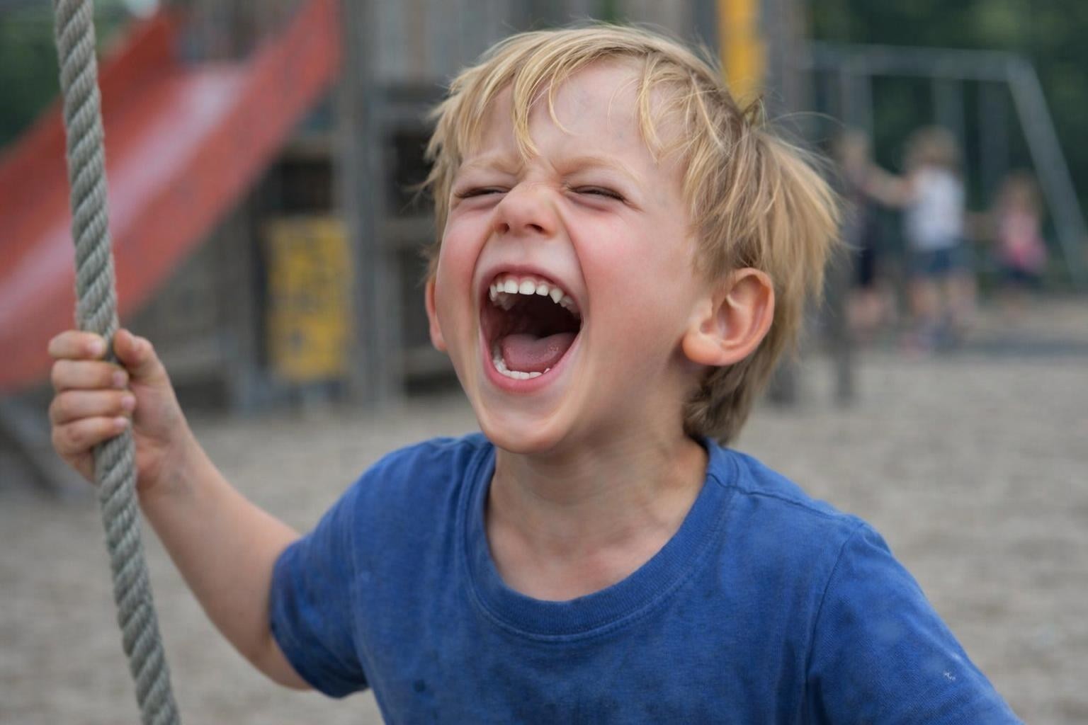 Young child gripping rope and shouting with mouth wide open